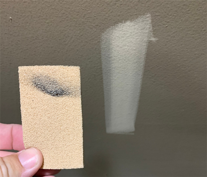 photo of a chemical sponge being used to take soot off wall; clean spot where sponge was used
