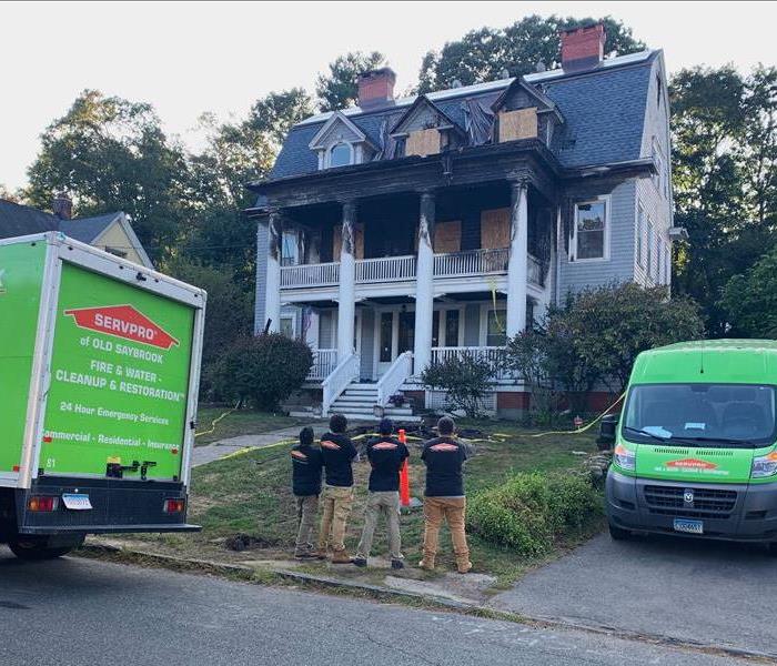 photo of a fire damaged house with SERVPRO crews and trucks in front of it